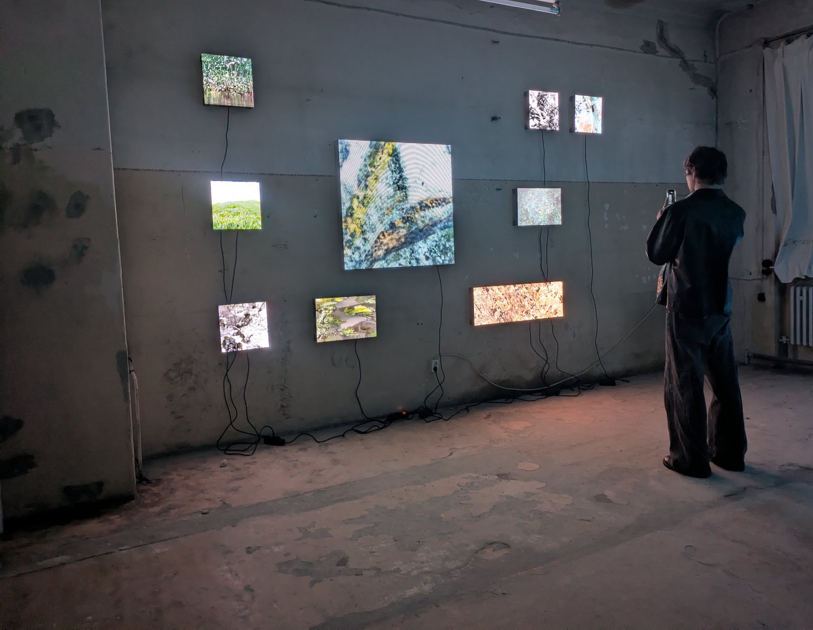 The same nine LED panels in the evening, a visitor standing in front of them