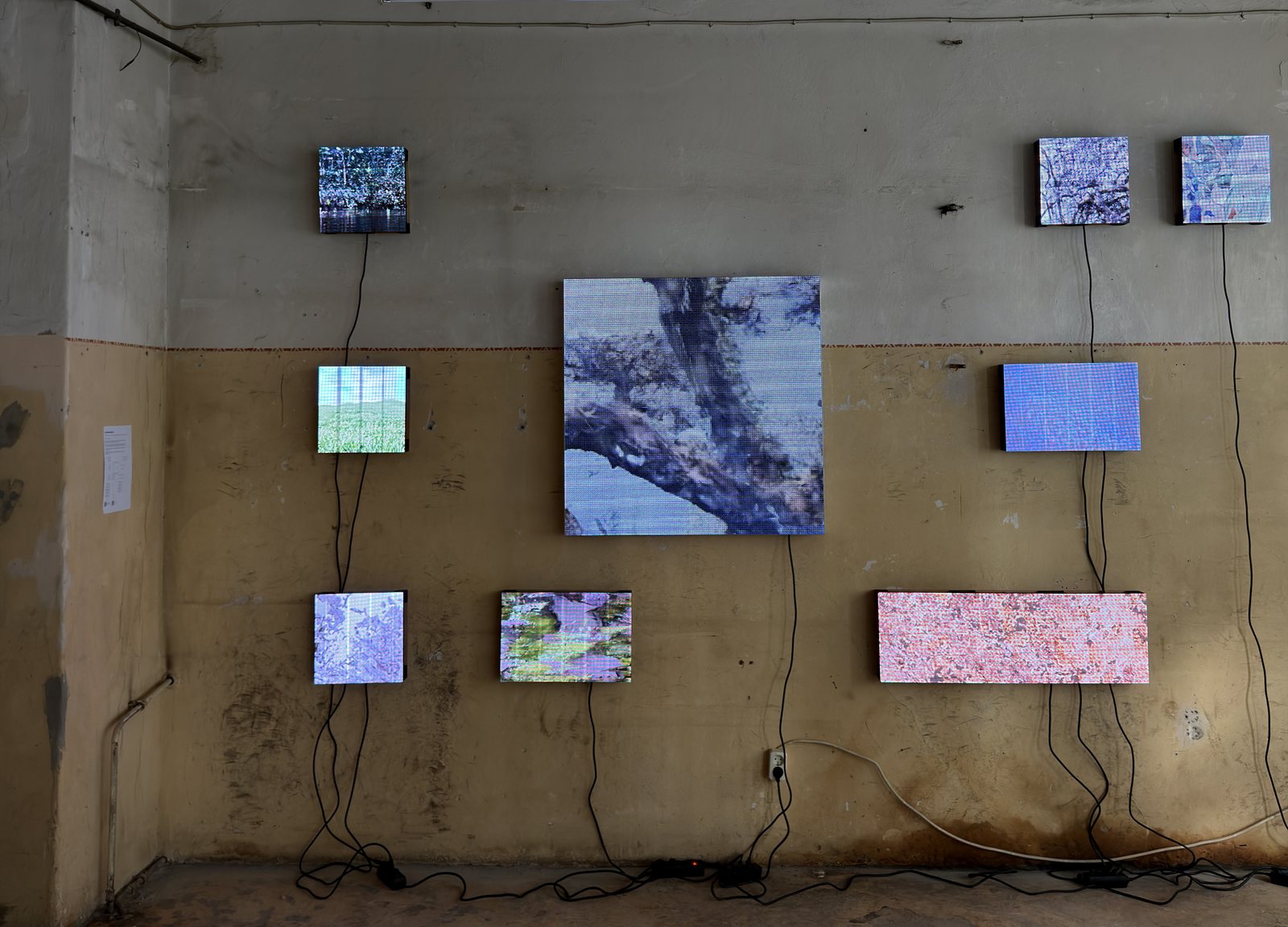Nine LED panels showing Synthetic Nature on a worn wall, daylight, LA18 Foundation, Berlin